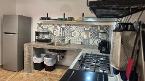 A compact kitchen with a built-in gas stove, a stainless steel refrigerator, and a patterned backsplash.