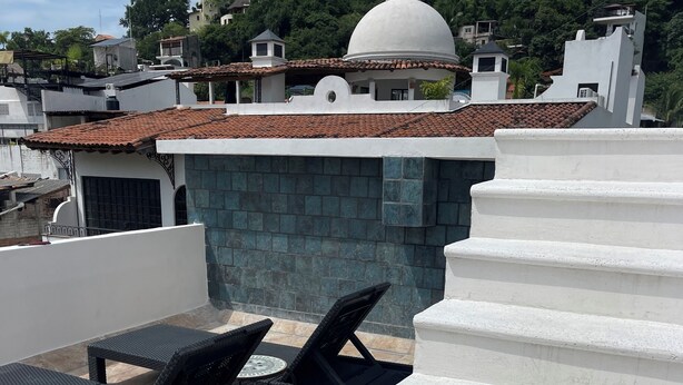 A rooftop terrace with outdoor furniture, a white dome structure, and a view of surrounding buildings.
