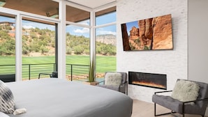 Une chambre avec un grand lit, une cheminée et une vue sur un terrain de golf.