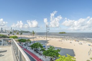 Une plage avec des parasols et des gens, une vue sur les gratte-ciel d'une ville en arrière-plan et un ciel dégagé.