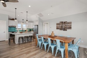 Una cocina moderna con armarios blancos, una isla de madera y un comedor con sillas azul claro.