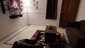Una sala de estar con un sofá, una mesa de centro, un televisor, un reloj y una puerta.