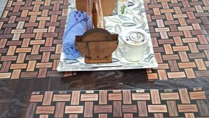 Una mesa con un posavasos tejido, un florero con flores, una bandeja de madera y una vela.