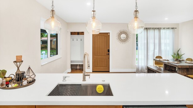 Una cocina moderna con una isla central, iluminación colgante y vistas al área de comedor.