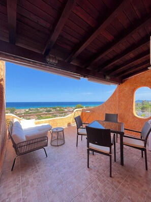 Terraço com vista para o mar, mobiliado com cadeiras e uma mesa.