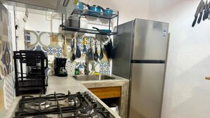 A kitchen with a gas stove, a stainless steel refrigerator, and a coffee maker.