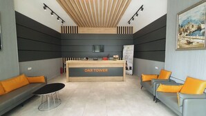 A reception area with a reception desk labeled "DAR TOWER," two sofas with orange cushions, a small round table, and a ceiling with wooden slats. - Enjoyable apartment with AC in charming Batumi (Batumi)