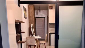 A compact hotel room with a bed, a small table with chairs, a kitchenette, and a door leading to another room. - Enjoyable apartment with AC in charming Batumi (Batumi)