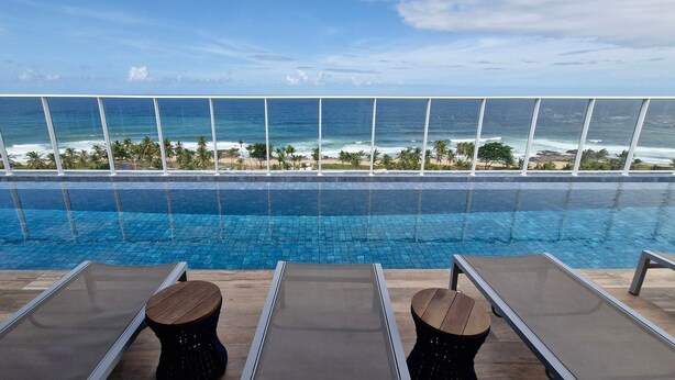 Un espace aménagé au bord de la piscine, avec des chaises longues et une vue sur l’océan.