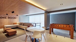Une salle de jeux moderne équipée d’un canapé, d’une table basse, de fauteuils et d’un baby-foot.