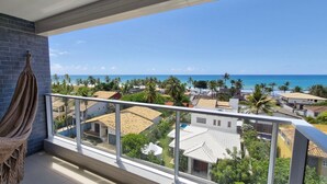 Un balcon donnant sur une plage, un hamac et un mur en briques.