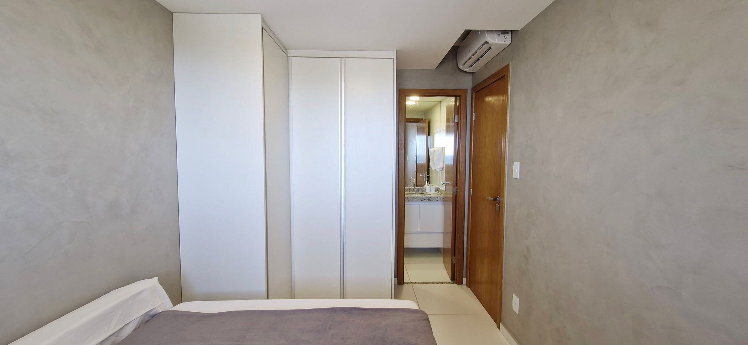 A bedroom with a bed, a wardrobe, and a bathroom visible through an open door.
