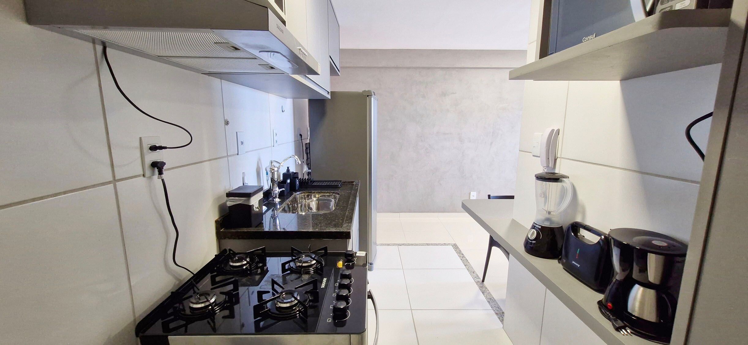 A compact kitchen with a gas stove, a blender, and a coffee maker on the countertop.