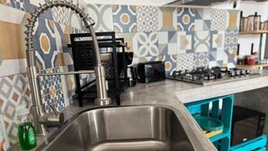 Eine Küche mit Spüle aus Edelstahl, einem modernen Wasserhahn und einer strukturierten Spritzschutzwand.