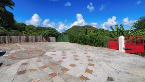 A paved area with a patterned tile design, a red gate, and a green fence. - Tropic Nook (Gros Islet)