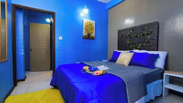 A bedroom with a bed, a bedside table, a nightstand, a wall-mounted artwork, and a door.