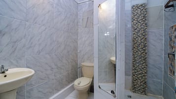 Un baño con suelo de mármol, inodoro, lavabo y zona de ducha.
