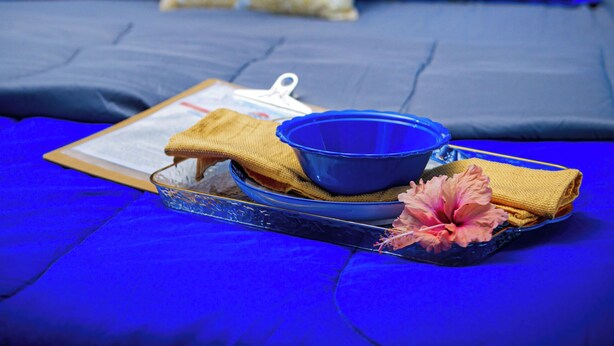 A bed with blue bedding, a white pillow, and a blue bowl on a tray. - Tropic Nook (Gros Islet)
