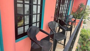 A balcony with black plastic chairs and a glass door.