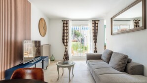 A living room with a sofa, a television, a coffee table, and a large mirror. - La Saltarelle - modern apartment 750m from the port (Cassis)