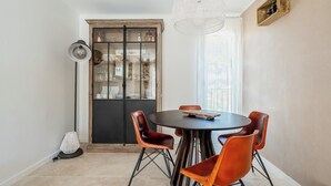 A dining area with a round table, six leather chairs, a floor lamp, and a decorative hanging light fixture. - La Saltarelle - modern apartment 750m from the port (Cassis)