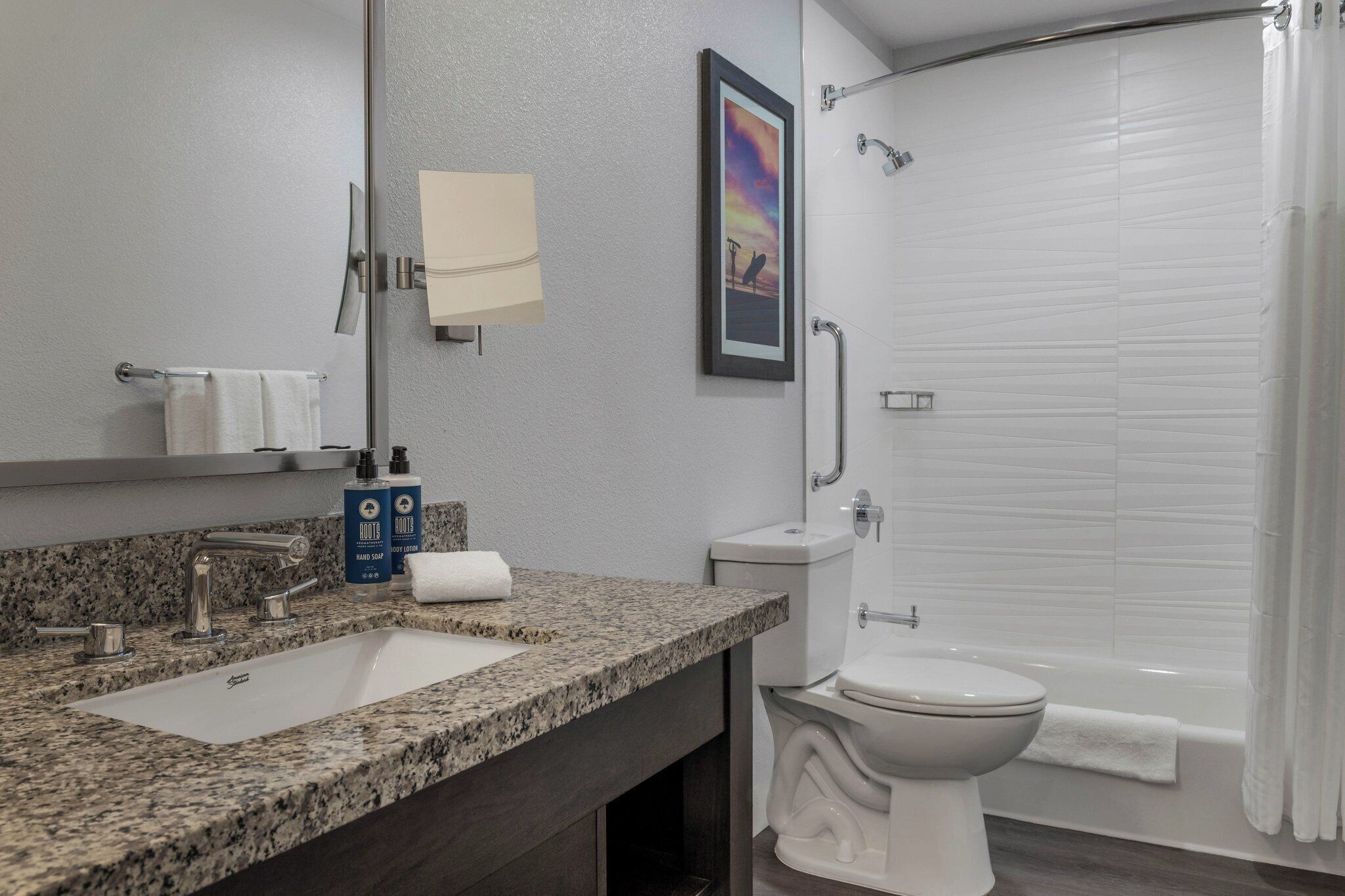 A bathroom with a granite countertop sink, a toilet, and a bathtub.