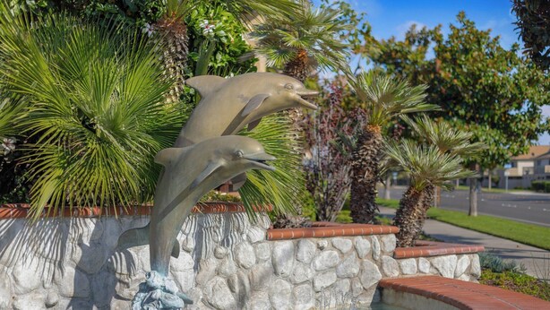 Una fuente con esculturas de delfines y un muro de piedra.