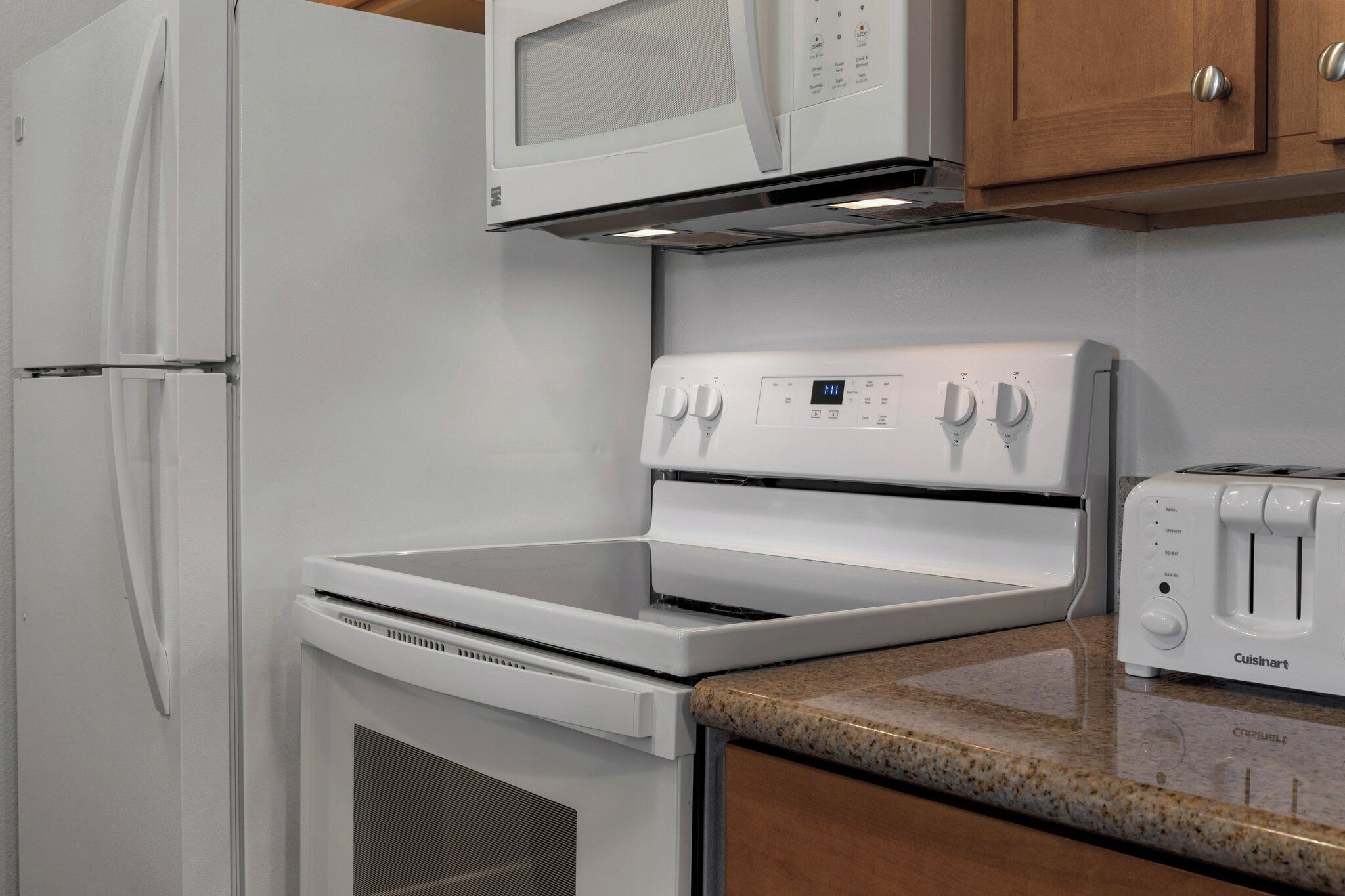 A kitchen with a white refrigerator, microwave, stove, and toaster.