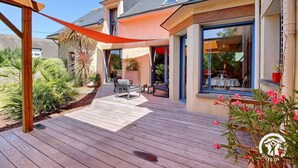 A modern house with a wooden deck, outdoor seating, and a large window overlooking the garden. - Saint Co - SARZEAU - Gîte (SARZEAU)