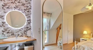 Een moderne badkamer met een ronde spiegel, een houten wastafelmeubel en een backsplash van geometrische tegels.