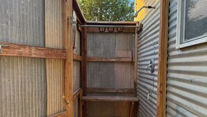 A narrow outdoor space with a wooden fence and a brick floor, leading to a corrugated metal building. - MESA VERDE CABIN I - Panoramic Views of Mesa Verde! (Mancos)