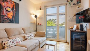 A modern living room with a sofa, two small tables, a TV displaying Netflix, and a balcony with a view. - Modern apartment just a 20-minute walk from the historic center of Lucca (Lucca)