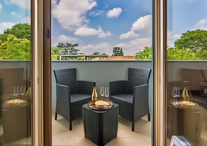 A balcony with two wicker chairs, a small table with a bottle and glasses, and a view of a green landscape. - Modern apartment just a 20-minute walk from the historic center of Lucca (Lucca)