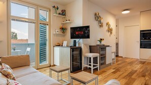 A modern living room with a sofa, a TV, and a kitchen area with a fridge and bar stools. - Modern apartment just a 20-minute walk from the historic center of Lucca (Lucca)