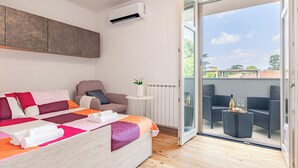 A modern bedroom with a bed, a chair, a small table, and a view of the outdoors through a glass door. - Modern apartment just a 20-minute walk from the historic center of Lucca (Lucca)