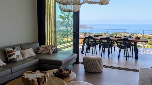 A modern living room with a large window overlooking a coastal view.