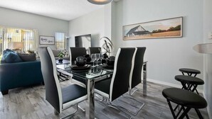 A modern dining area with a glass table, black and white chairs, and a painting on the wall. - Quiet Resort 3BR Nature Walk 20min to Disney (Kissimmee)