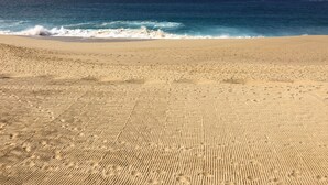 Ein sandiger Strand mit Fußspuren, die zum Meer führen.