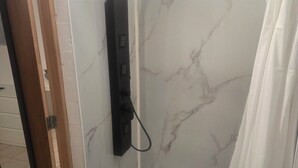 A bathroom with a shower, a sink, and a mirror.