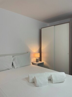 A hotel room with a bed, a nightstand with a lamp, and a wardrobe.