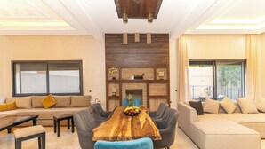 A modern living room with a wooden dining table, sofas, and a fireplace. - Villa in the heart of Marrakech city center, with a private pool. (Marrakesh)