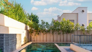 A swimming pool with clear water, surrounded by a low wall with climbing plants. - Villa in the heart of Marrakech city center, with a private pool. (Marrakesh)