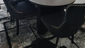 Een eettafel met stoelen, een schaal met snacks en een afstandsbediening op de tafel.