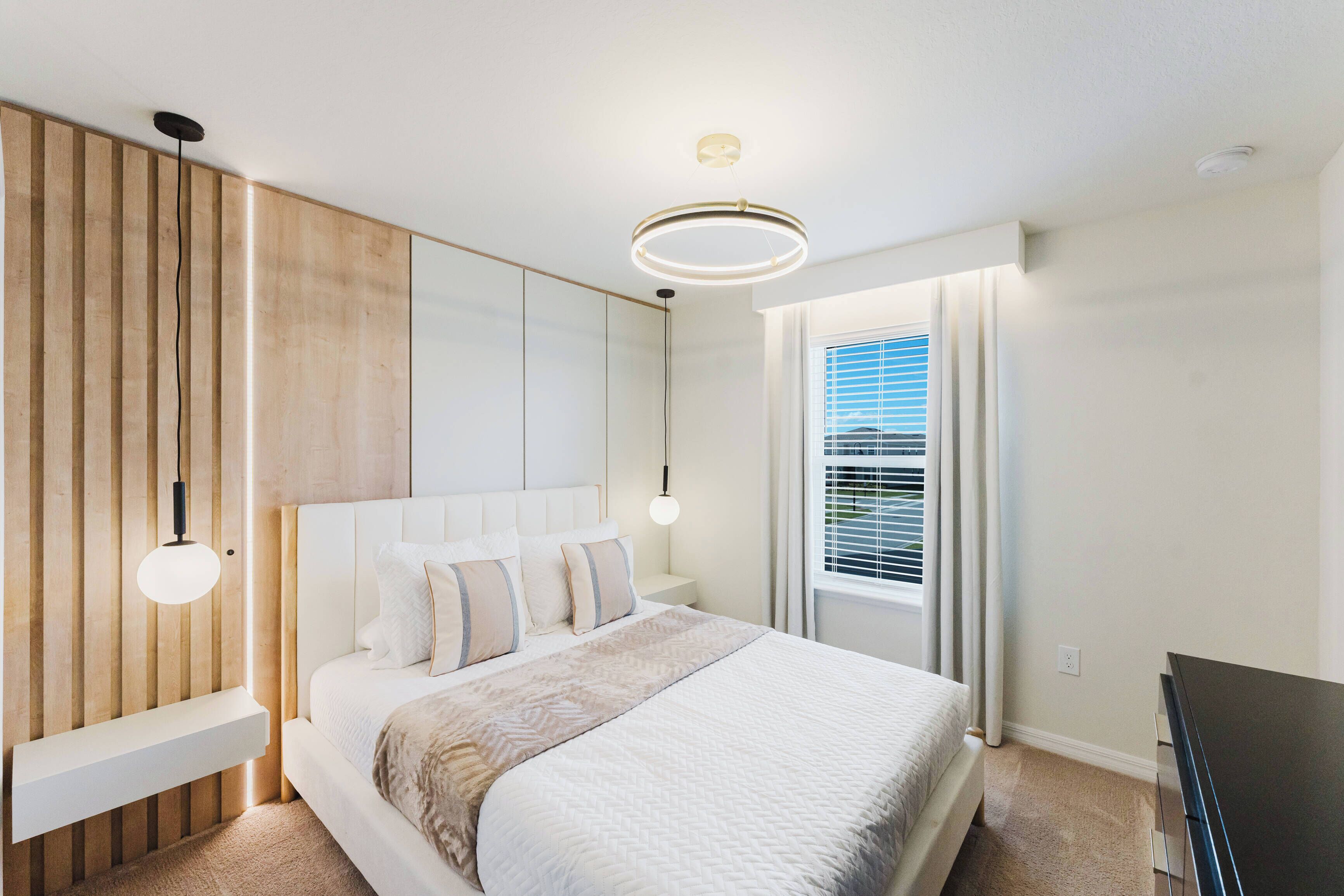 Une chambre à coucher moderne, avec un lit, des tables de chevet, une armoire intégrée et un luminaire au plafond.