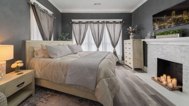 A bedroom with a bed, nightstand, dresser, and fireplace. - "KOZY KOTTAGE" Near Downtown! 2025 Remodel, Sleeps 8 Comfortably, Games & More! (Denison)