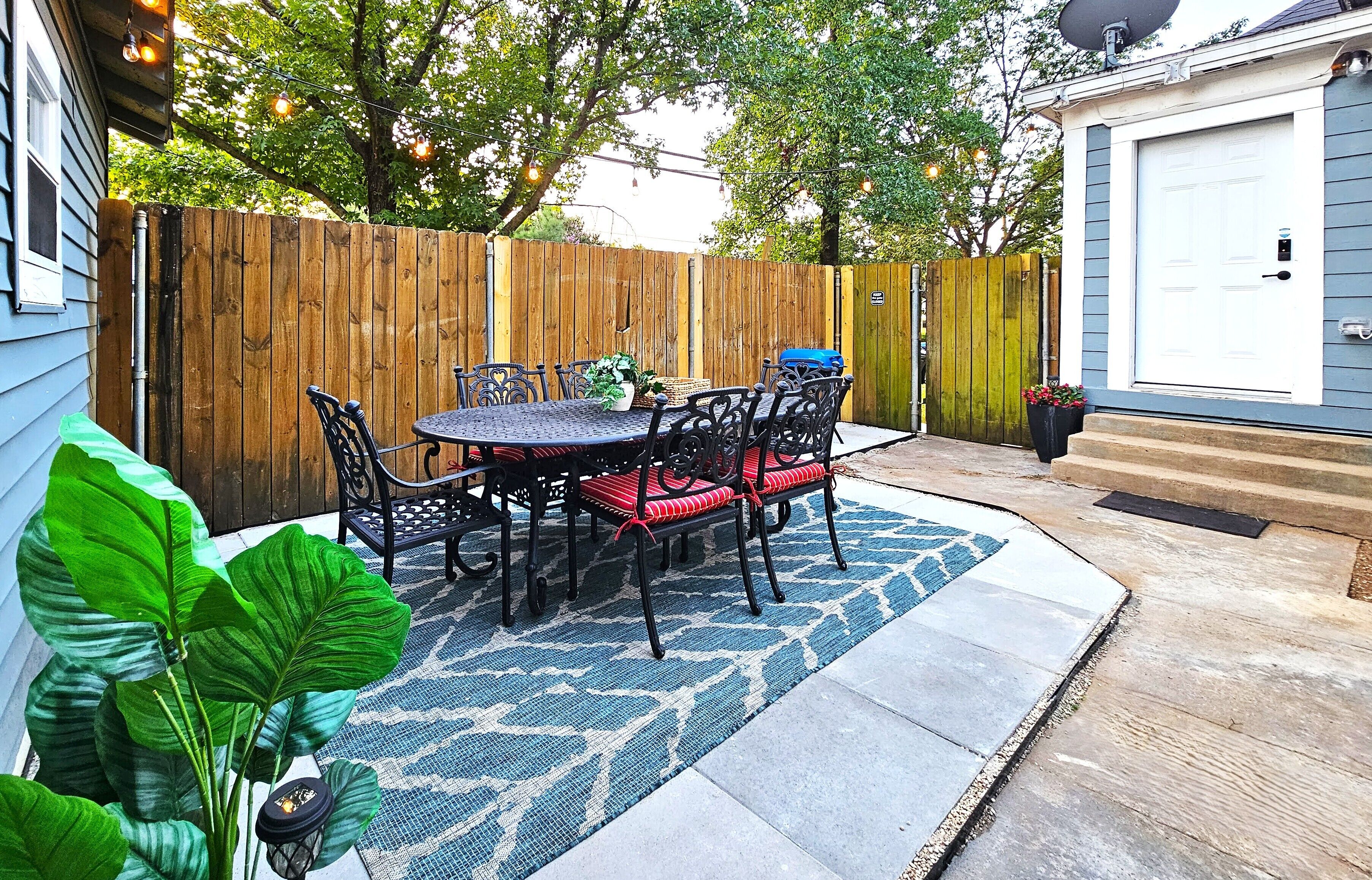 A patio with a table and chairs, a wooden fence, and a house with a garage door.