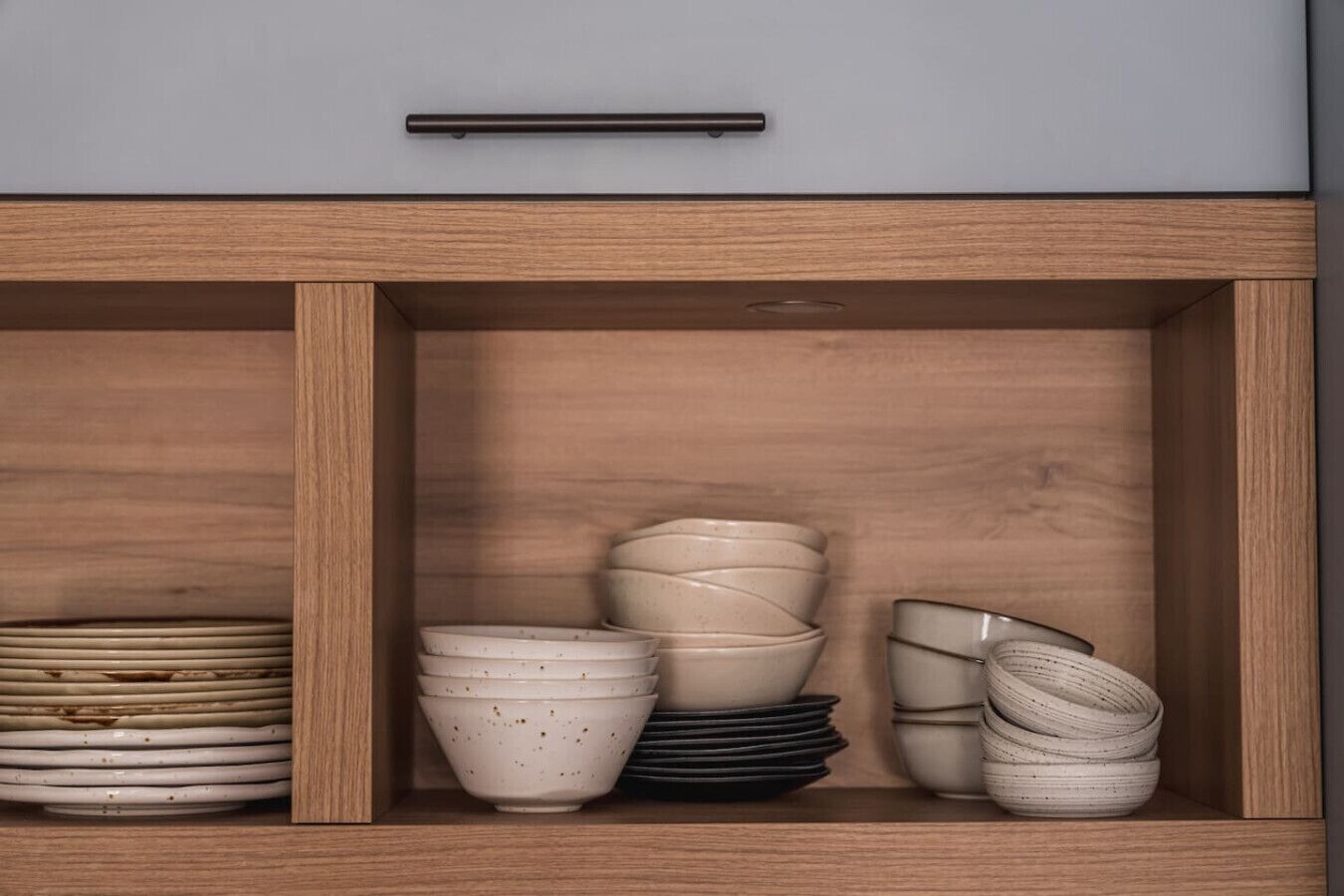 A wooden cabinet with multiple compartments containing stacked bowls and plates.