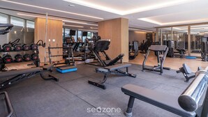 A modern gym with various exercise equipment, including dumbbells, benches, and cardio machines.