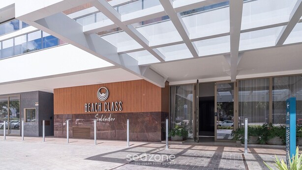 A modern building with a 'Beach Class' sign, large windows, and a covered entrance area.