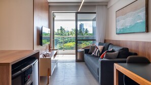 A modern living room with a sofa, a coffee table, a TV, and a kitchen area with a dishwasher.